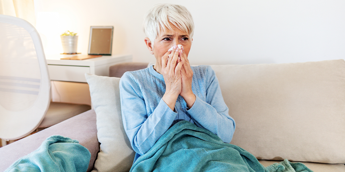 Eine Frau liegt auf dem Sofa mit einer Decke und schnäuzt in ein Taschentuch Eine Frau liegt auf dem Sofa mit einer Decke und schnäuzt in ein Taschentuch
